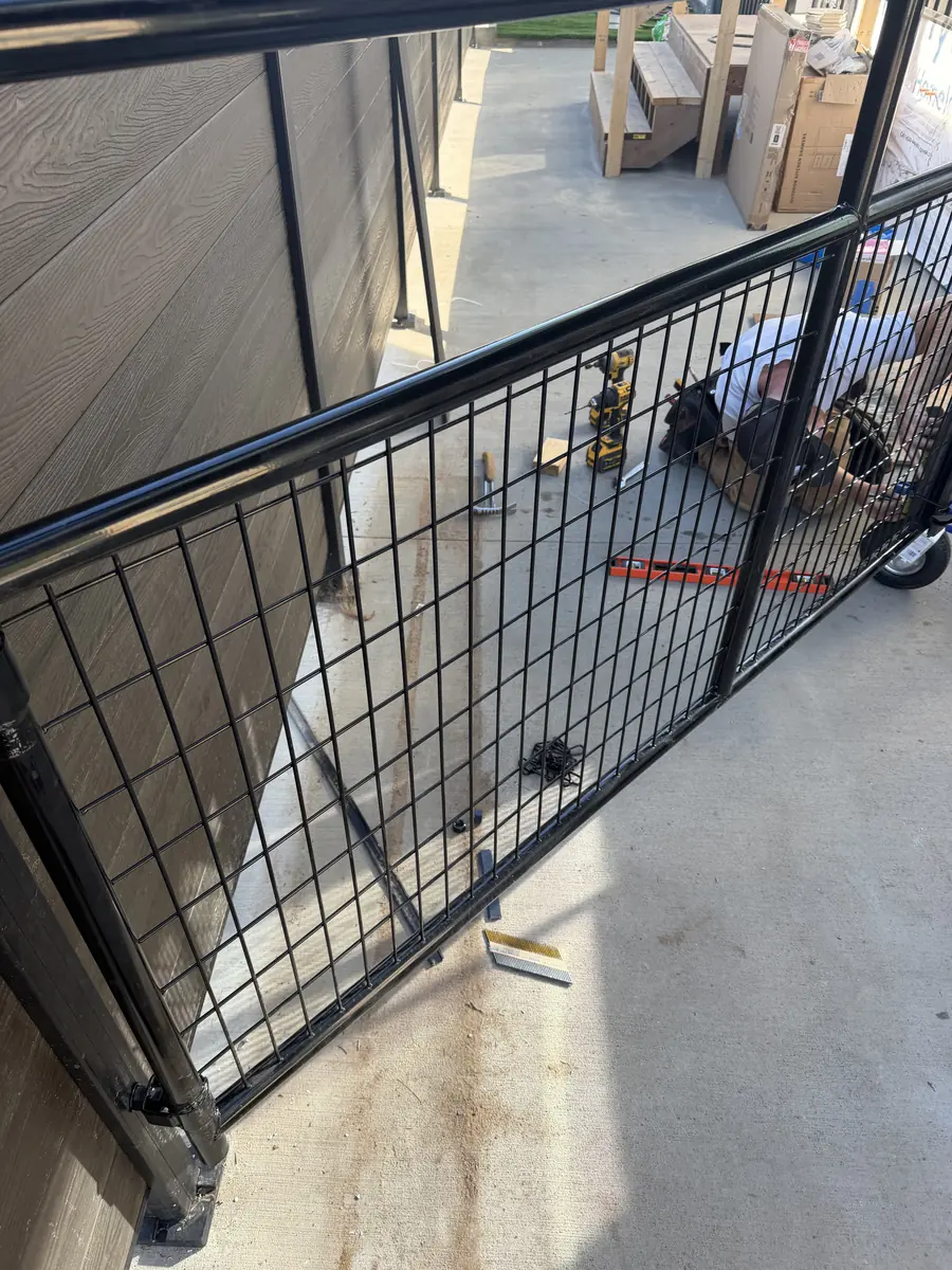 Bare black steel gate frame with wire panel before cladding